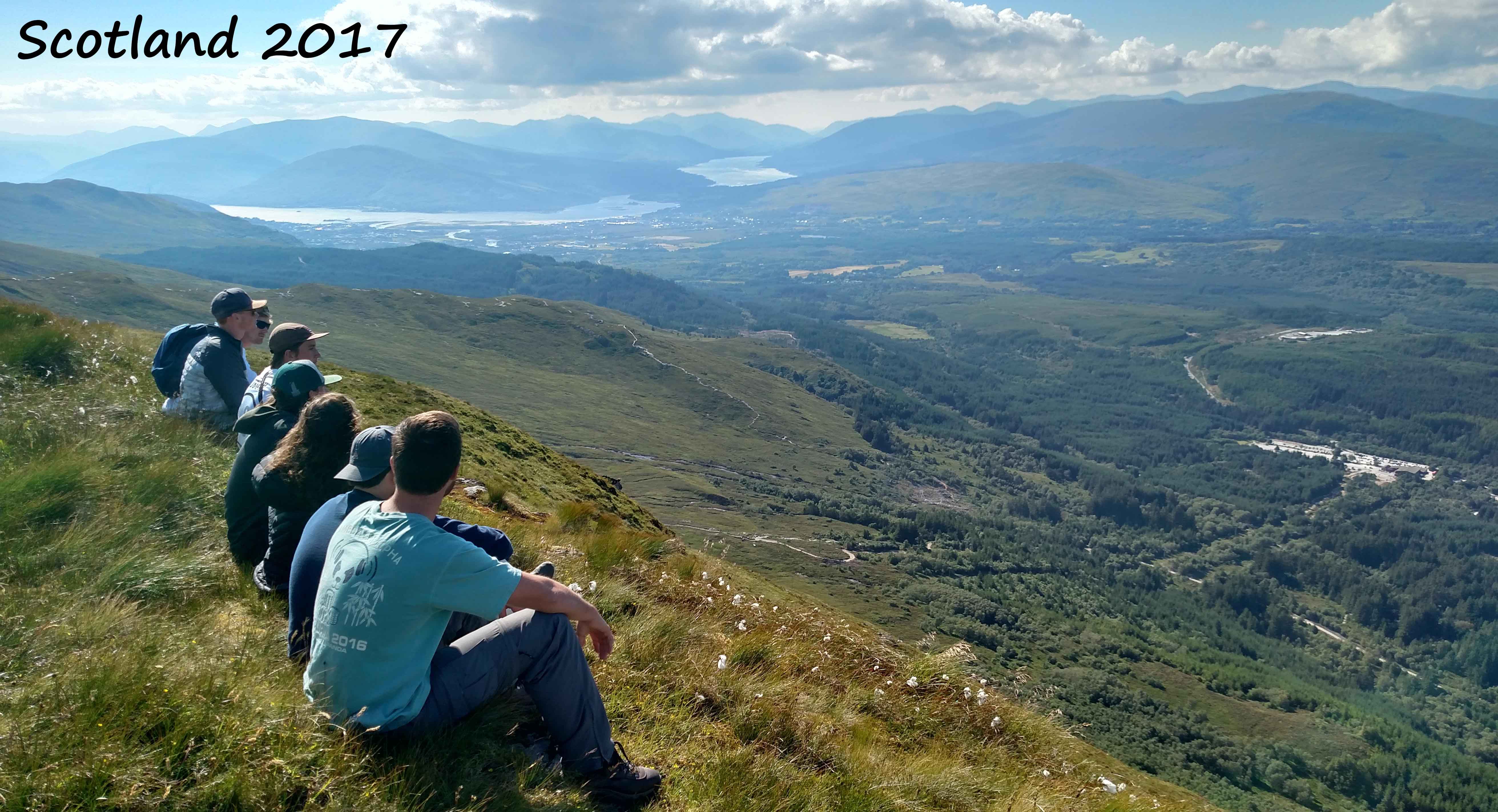 Geosciences students sitting on a hill in Scotland overlooking the land